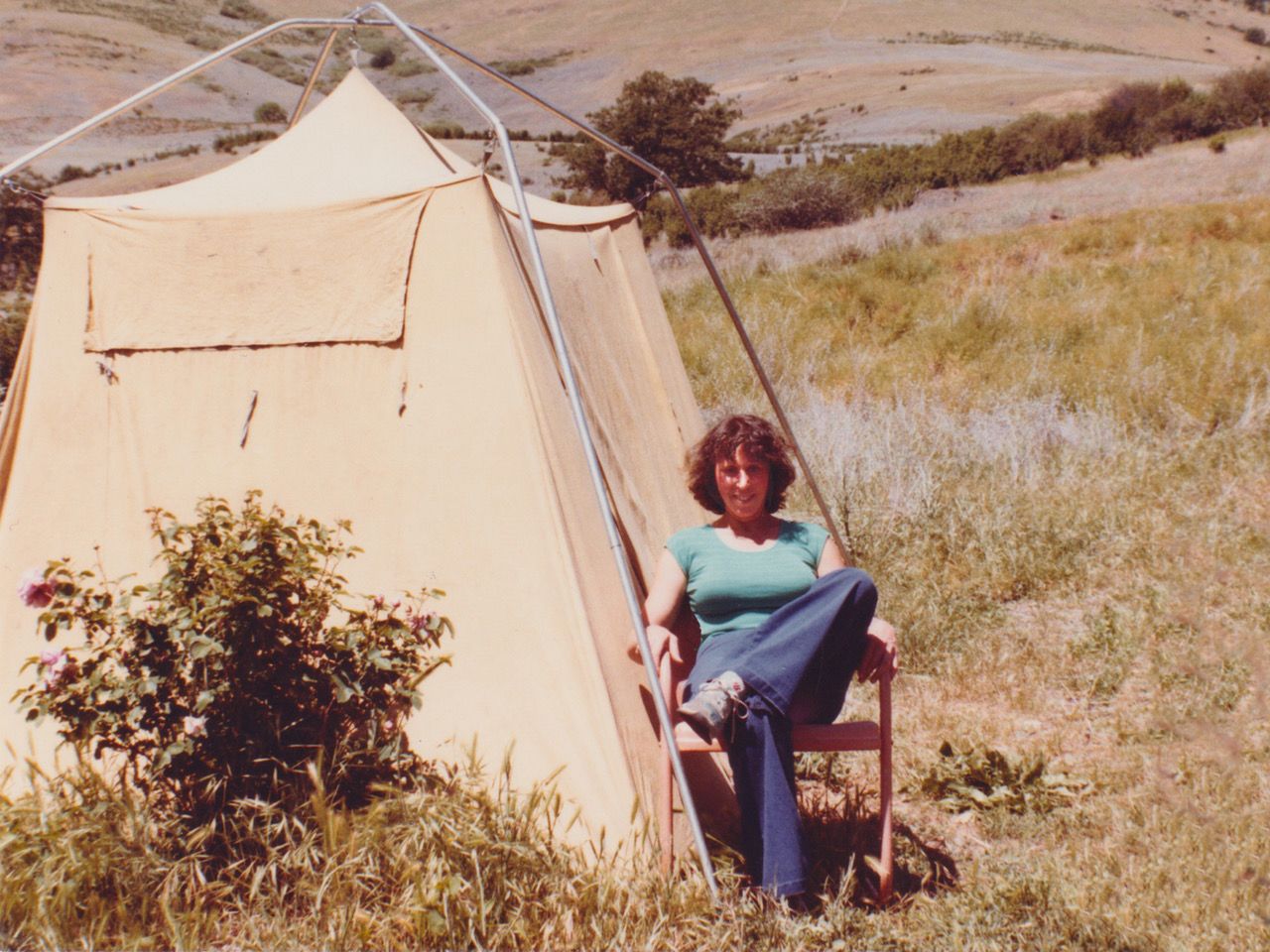 Dorothy sitting next to her tent while camping.